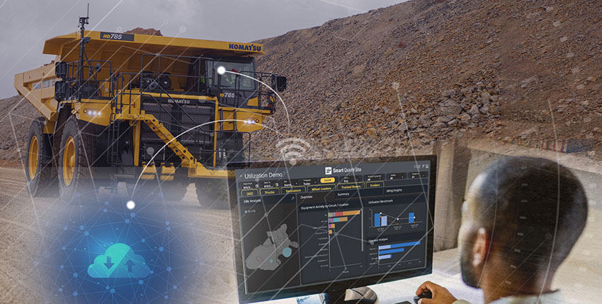 man using smart quarry technology on a computer with cloud and wifi imagery in front of a komatsu truck